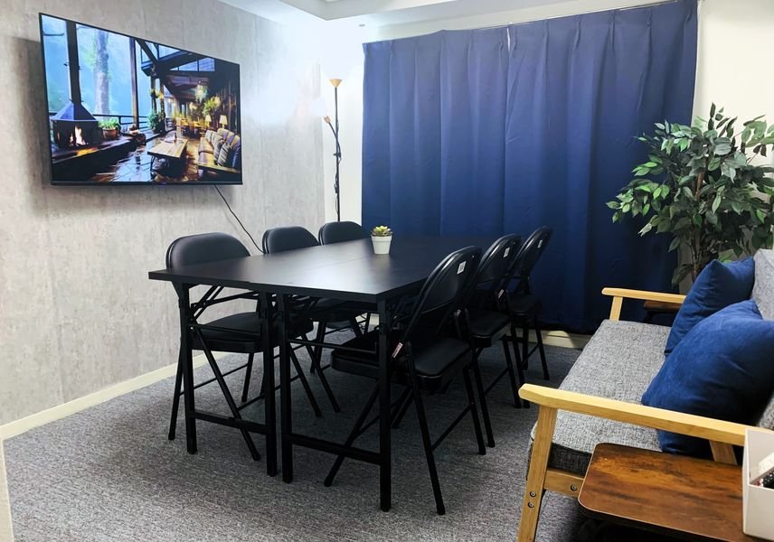 floo lounge 浜松町の室内。6人掛けのテーブルと50型モニター、ソファのある貸切スペース